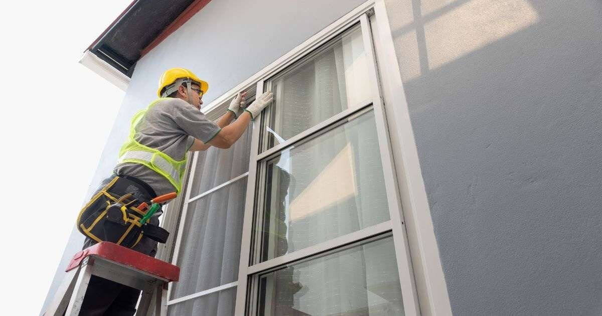 Window installation: Worker installing a window on a building exterior.